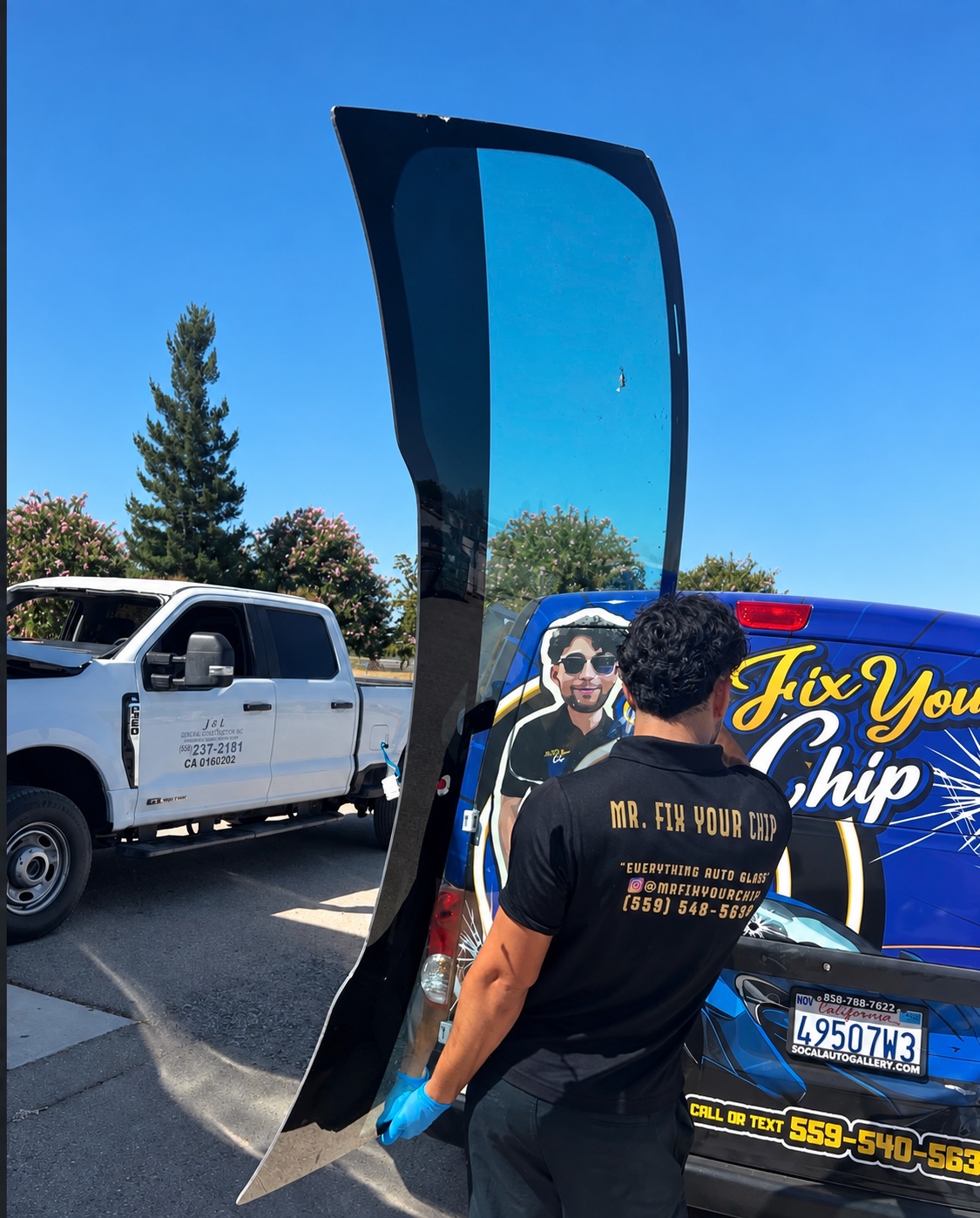 Mr. Fix Your Chip technician carrying replacement door glass beside the mobile service van