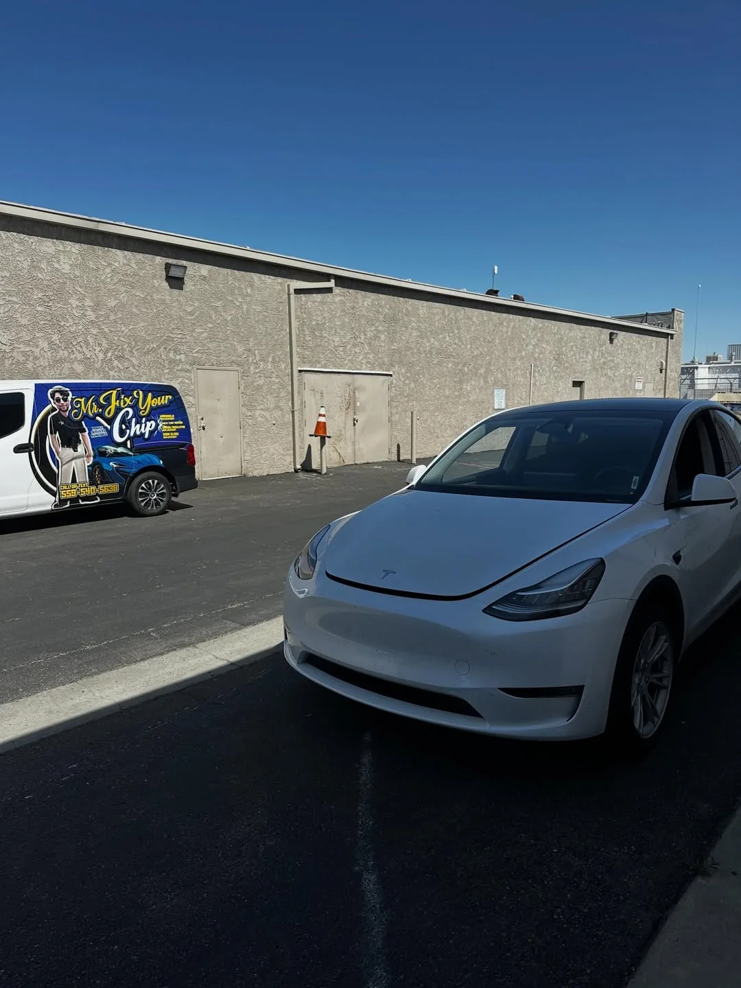 White electric vehicle beside the Mr. Fix Your Chip van